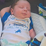 Liam is registered to the contest to win money with this photo: newborn, baby, sleeping, infant, portrait, indoors, blanket, diaper, sports_shirt, clothing, face, head, person, couch, textile, pink_device, colorful, resting, closeup, photograph