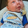 baby, infant, child, portrait, lying_down, pacifier, smiling, wide_eyed, blanket, couch, clothing, sports_jersey, detroit_lions, football, blue, white, indoors, close_up, face, happy