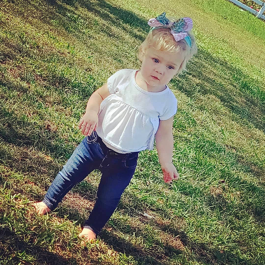 Kasey is registered to the contest to win money with this photo: baby_toddler_clothing, eyewear, grass, grass_family, grassland, happy, human_leg, lawn, meadow, mountain, people_in_nature, person, sleeve, sportswear, summer, sunlight, t_shirt, tints_and_shades, toddler, waist
