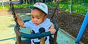 Jesse is registered to the contest to win money with this photo: toddler, child, swing, playground, cap, shorts, tshirt, mickey_mouse, shoes, outdoor, trees, fence, sunlight, shade, play, park, metal_chains, rubber_surface, summer, daytime