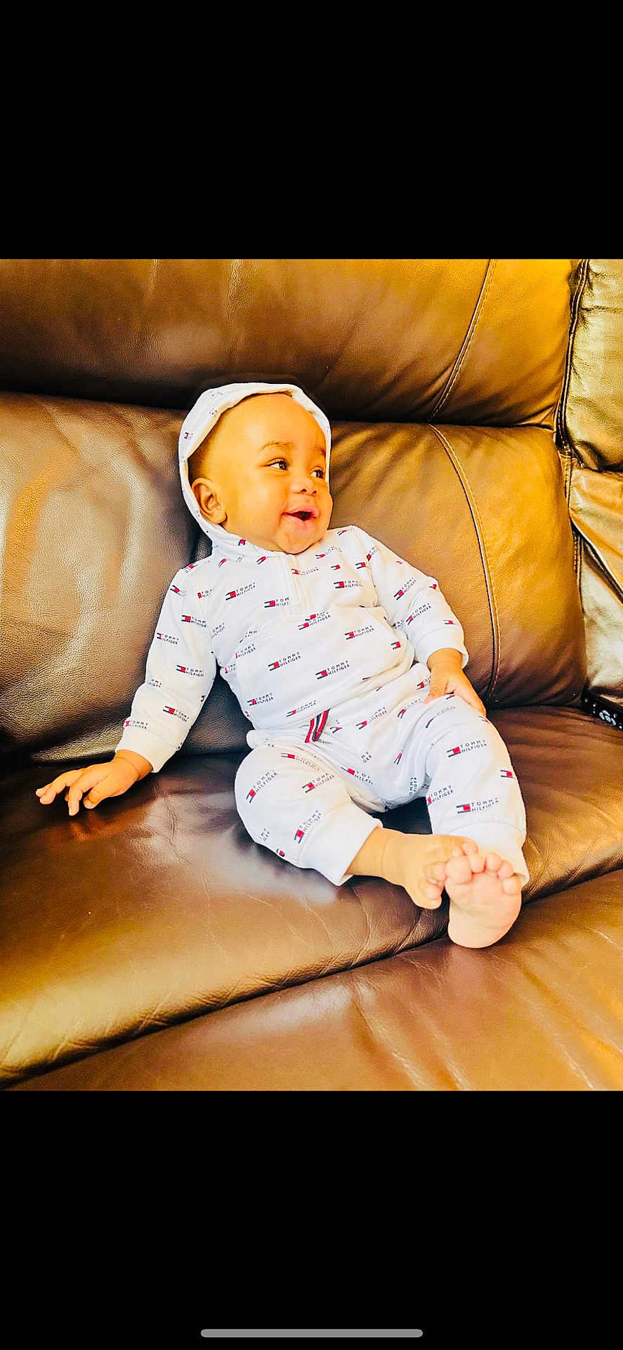 Jesse joined the competition — help win amazing prizes! baby, child, smiling, hoodie, white_clothing, tommy_hilfiger, leather_couch, brown, sitting, happy, indoors, foot, hand, casual, cute, portrait, infant, relaxing, comfortable, young