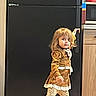 Annalea is registered to the contest to win money with this photo: child, girl, toddler, walking, standing, portrait, indoors, kitchen, refrigerator, fashion, dress, brown_clothing, leopard_print, tights, blonde_hair, long_hair, facial_expression, barefoot, wooden_floor, home