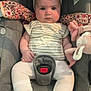 baby, car_seat, infant, plush_toy, headband, white_clothing, striped_shirt, seatbelt, child, indoors, soft_toy, footwear_free, cushioned_seat, cute, person, sitting, young_child, serious_expression, baby_girl, fabric