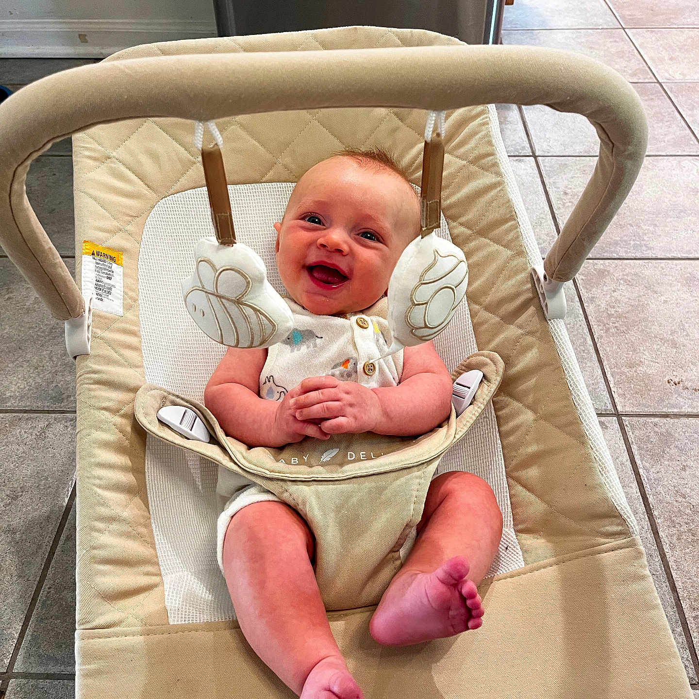 Connor is registered to the contest to win money with this photo: baby, smiling, infant, baby_bouncer, toy, hanging_toys, indoor, floor_tiles, happy, clothing, seat, infant_smile, child, cute, baby_girl, baby_boy, playtime, home, person, portrait