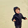 child, smiling, hoodie, barefoot, sand, beach, footprints, happy, outdoor, nature, person, casual_clothing, young, playful, joyful, misty, sand_dunes, portrait, full_body, daylight