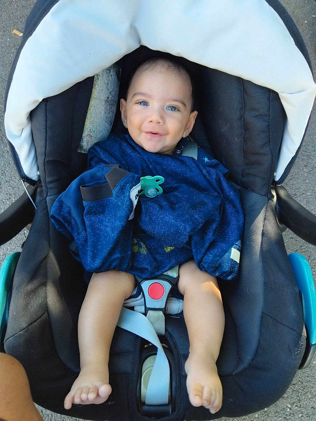 Hayden a rejoint le concours — aidez-le/la à gagner de superbes lots ! baby, child, car_seat, blue_clothing, pacifier, barefoot, smiling, infant, safety_harness, outdoor, person, cute, happy, seat, foot, head, face, baby_clothes, transport, daylight