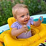 child, toddler, inflatable, pool_float, yellow, toy, blue_eyes, smiling, outdoor, summer, water, play, garden, brick_wall, happy, clothing, person, baby, fun, sunlight