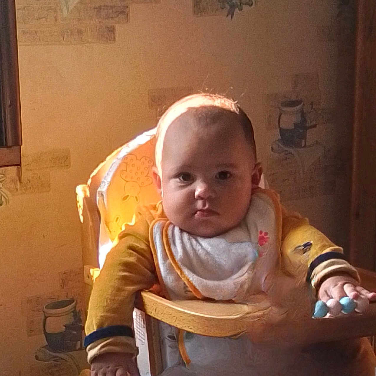 Lucas a rejoint le concours — aidez-le/la à gagner de superbes lots ! baby, beads, bib, child, face, furniture, hand, high_chair, home, indoor, infant, person, portrait, seated, serious_expression, sunlight, wallpaper, window, wood, yellow_clothing