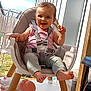 Zyha participe au concours pour gagner de l'argent avec cette photo : baby, high_chair, child, smiling, snack, doll, outdoor, sunny, happy, seatbelt, clothing, foot, toy, person, daylight, modern_building, grass, fence, playful, expression
