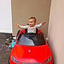 Zyha participe au concours pour gagner de l'argent avec cette photo : toddler, child, toy_car, red_car, audi, roadster, outdoor, smiling, happy, play, small_child, vehicle, wheels, hands_up, casual_clothing, concrete, wall, shoes, toys, daylight