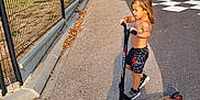 Lyham participe au concours pour gagner de l'argent avec cette photo : child, scooter, outdoor, sunlight, shadow, fence, trees, road, shorts, shoes, bare_chest, sidewalk, play, summer, casual, nature, happy, boy, recreation, daytime