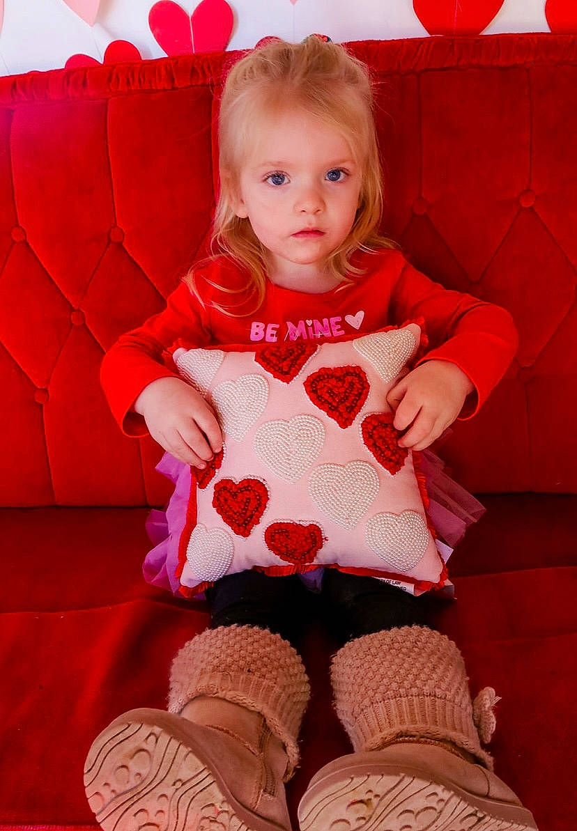 Adaleigh is registered to the contest to win money with this photo: arm, baby_toddler_clothing, dress, head, human_leg, knee, lap, leg, magenta, organ, pattern, person, pink, red, sitting, skin, sleeve, sock, t_shirt, thigh