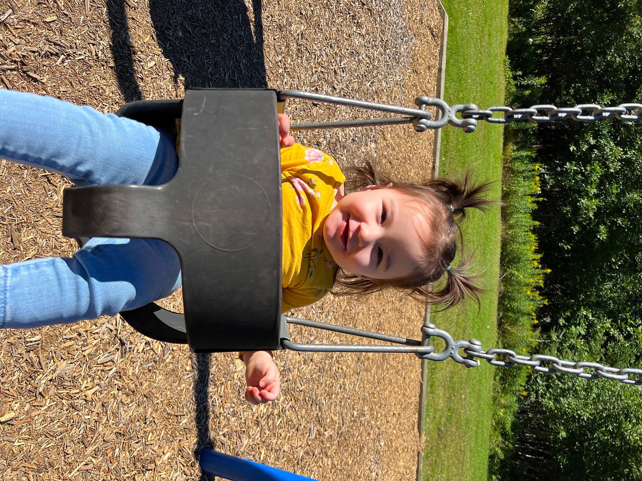 Kamryn is registered to the contest to win money with this photo: child, city, electric_blue, fence, fun, grass, happy, leisure, outdoor_play_equipment, people_in_nature, person, play, playground, recreation, smile, soil, t_shirt, toddler, tree, wood