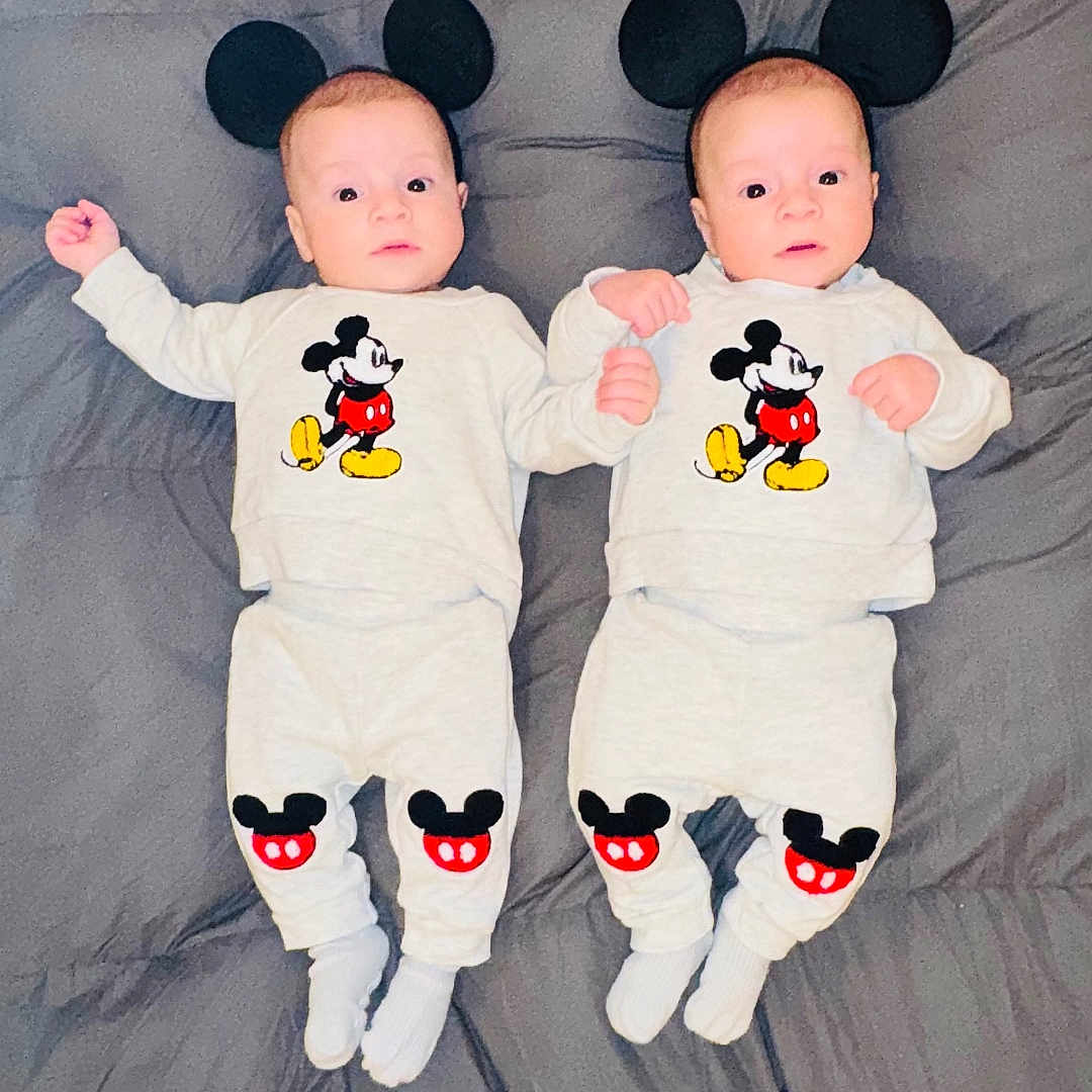 Vega is registered to the contest to win money with this photo: baby, bed, black_ears, blanket, cartoon_character, child, costume, cute, footwear, indoor, infant, lying_down, matching_outfits, mickey_mouse, people, portrait, sleepwear, twins, two_babies, white_clothing