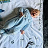 baby, infant, blue_onesie, blanket, numbers, deer_antlers, smiling, laughing, lying_down, cozy, soft_texture, play_mat, child, cute, happy, indoor, infant_clothing, person, head, pale_skin