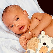 Jaylen joined the competition — help win amazing prizes! baby, infant, child, portrait, smiling, lying_down, blanket, white_blanket, plush_toy, stuffed_animal, giraffe_toy, bed, indoors, close_up, face, eyes, hands, bare_arms, happy, photography