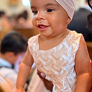 Melissa is registered to the contest to win money with this photo: baby, child, infant, portrait, smiling, happy, dress, headband, bow, pink, white, earring, indoor, event, railing, standing, crowd, celebration, fashion, closeup