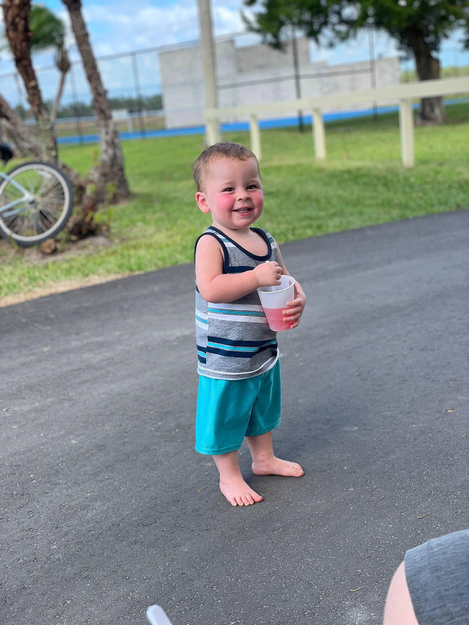 Bentley is registered to the contest to win money with this photo: asphalt, baby, barefoot, bicycle, bicycle_wheel, child, fun, gesture, grass, happy, joy, leisure, outdoor_recreation, person, plant, recreation, road, shorts, tire, toddler