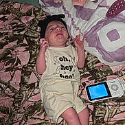 Xalia is registered to the contest to win money with this photo: baby, infant, onesie, headband, blanket, camo_pattern, baby_monitor, lying_down, expression, indoor, fabric, clothing, newborn, person, cute, small, sleepwear, pink, green, soft