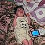 baby, infant, onesie, headband, blanket, camo_pattern, baby_monitor, lying_down, expression, indoor, fabric, clothing, newborn, person, cute, small, sleepwear, pink, green, soft