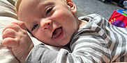 Sam joined the competition — help win amazing prizes! baby, child, smiling, striped_clothing, indoor, toy, happy, face, head, person, lying_down, cushion, carpet, colorful, play, infant, cheerful, closeup, cozy, cute