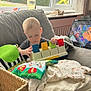 Sam is registered to the contest to win money with this photo: toddler, child, toy, piano, couch, blanket, tablet, cartoon, window, indoor, curtain, play, colorful, furniture, cozy, clothing, person, young_child, relaxing, daylight