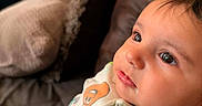 Rose joined the competition — help win amazing prizes! baby, infant, child, portrait, face, eyes, smiling, indoor, couch, cushions, blanket, clothing, onesie, patterned_clothing, cartoons, colorful, sitting, close_up, home, relaxed