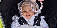 Amelia-Faith joined the competition — help win amazing prizes! baby, stroller, blanket, hoodie, pink_bow, beads, outdoor, grass, fence, child, smiling, cozy, cute, person, infant, warm_clothing, baby_accessory, portrait, happy, seatbelt