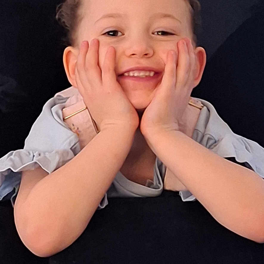 Kydine joined the competition — help win amazing prizes! black_background, casual_clothing, child, close_up, curly_hair, cute, expression, face, hands, happy, human, indoor, innocence, joy, person, portrait, relaxed, resting, smile, young