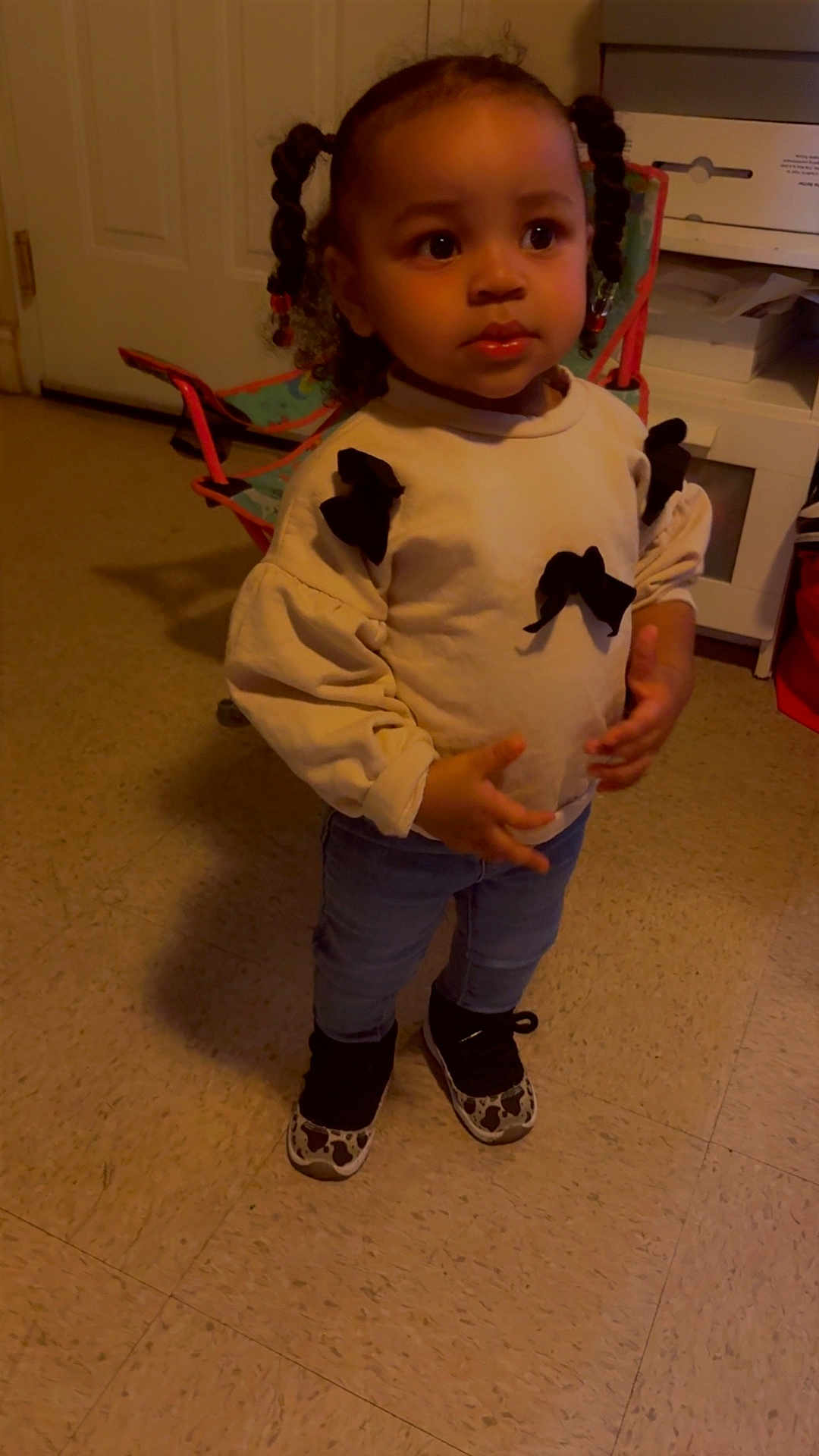 Delynn joined the competition — help win amazing prizes! bows, casual_clothing, chair, child, curly_hair, expression, floor, furniture, hair, home, indoor, jeans, person, room, sneakers, standing, sweater, toddler, toy_chair, young_child