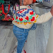 Delynn joined the competition — help win amazing prizes! toddler, child, indoor, braided_hair, beads, colorful_sweater, hearts_pattern, jeans, frilly_leggings, red_shoes, wooden_floor, standing, side_view, household_items, laundry_basket, bag, toy, wall, floor, person