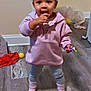Delynn is registered to the contest to win money with this photo: toddler, child, indoors, pink_hoodie, lollipop, standing, wooden_floor, curly_hair, playful, snack, cozy_clothing, socks, home, casual, floor, person, young_child, cute, curious, small