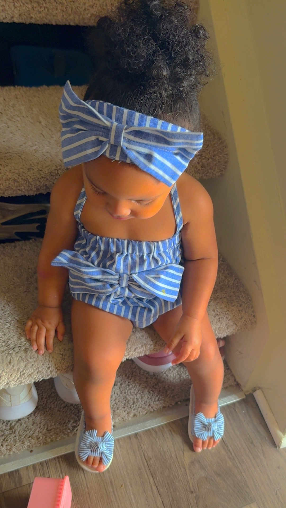 Delynn is registered to the contest to win money with this photo: toddler, child, striped_clothing, headband, curly_hair, stairs, carpet, sandals, blue, indoor, wooden_floor, small_toys, cute, baby, sitting, looking_down, hands, legs, toes, home