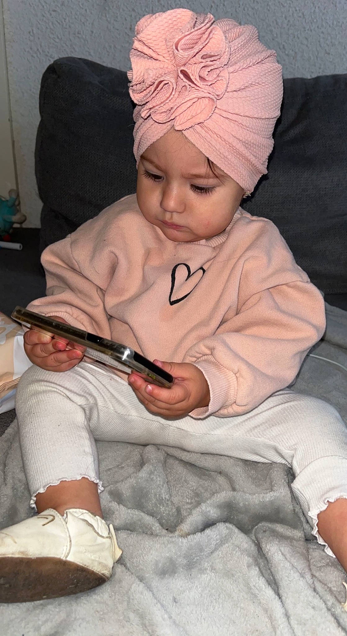 Kélya a rejoint le concours — aidez-le/la à gagner de superbes lots ! baby, baby_toddler_clothing, beanie, cap, child, comfort, finger, headwear, knit_cap, lap, mobile_phone, nail, pattern, person, room, sitting, sleeve, toddler, white, wool