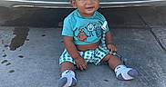 Kaida joined the competition — help win amazing prizes! toddler, child, baby, sitting, smiling, curly_hair, blue_shirt, checkered_shorts, socks, car, license_plate, concrete, driveway, tire_marks, water_spots, toy, outdoor, daylight, front_view, person