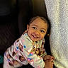 Eliana joined the competition — help win amazing prizes! toddler, child, smile, pajamas, happy, indoor, blanket, chair, baby, face, person, cozy, expression, cute, young, clothing, warm, home, infant, playful