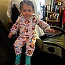 Eliana joined the competition — help win amazing prizes! toddler, child, pajamas, colorful_clothing, sitting, recliner, blanket, living_room, trophies, flowers, furniture, smiling, face, person, indoors, shoes, hair_beads, decor, table, photography