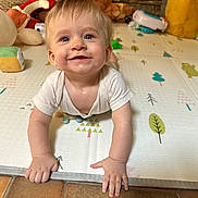 Marceau a rejoint le concours — aidez-le/la à gagner de superbes lots ! baby, child, crawling, play_mat, toy, plush_toy, indoor, happy, smiling, blue_eyes, short_hair, floor, tile_floor, white_shirt, hands, face, person, home, childhood, cute