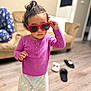 toddler, child, sunglasses, heart_shaped, purple_top, pajama_pants, curly_hair, living_room, slippers, couch, wooden_floor, indoor, person, fashion, cute, standing, home, casual_clothing, young_child, playful