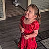 beads, blue_shoes, brick_wall, carpet, cartoon_character, casual_clothing, child, curious_expression, doorway, floor, girl, home_interior, indoor, pony_tail, red_dress, socks, standing, step_stool, wood_floor, young_child