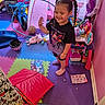 Ashley is registered to the contest to win money with this photo: basketball, child, clothing, colorful, floor_mats, fun, girl, happy, helmet, home, indoors, pigtails, pink, play, playroom, purple, smiling, standing, tent, toys