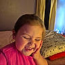 bed, casual, child, cozy, curtain, curtains, expression, face, hand, happy, home, indoor, laughing, person, pillow, pink_shirt, smiling, soft_lighting, wall, young_child