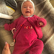 Alba a rejoint le concours — aidez-le/la à gagner de superbes lots ! baby, infant, smiling, pink_clothing, knitted_outfit, headband, pacifier, blanket, hand, cozy, soft_texture, lying_down, cute, child, indoors, warm_colors, comfort, portrait, happy, young_child