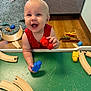 Waylen is registered to the contest to win money with this photo: baby, bodypart, clothing, face, finger, footwear, furniture, hand, happy, hardwood, head, laughing, person, photography, plywood, portrait, shoe, table, toy, wood