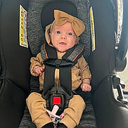 Leila joined the competition — help win amazing prizes! baby, car_seat, child, infant, seatbelt, headband, bow, clothing, black_socks, beige_outfit, sitting, strapped_in, indoors, curious_expression, wide_eyes, safety, cute, small_hands, pacifier, fabric_texture