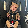 baby, car_seat, child, infant, seatbelt, headband, bow, clothing, black_socks, beige_outfit, sitting, strapped_in, indoors, curious_expression, wide_eyes, safety, cute, small_hands, pacifier, fabric_texture