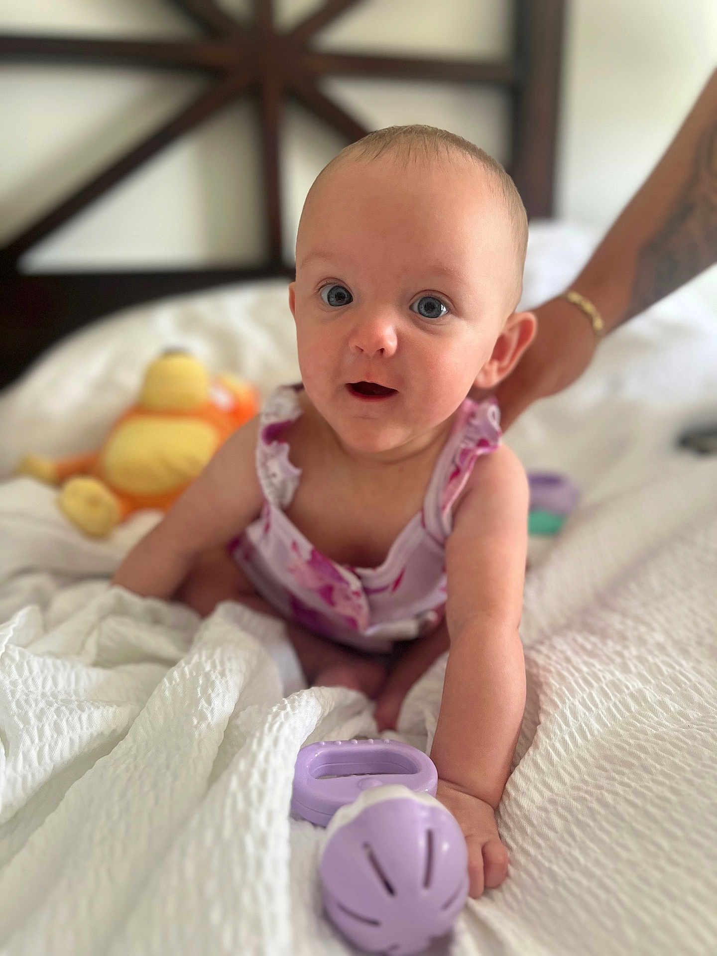 Leila is registered to the contest to win money with this photo: baby, infant, toy, bed, blanket, purple, hand, person, cute, smiling, indoor, soft, skin, clothing, expression, arm, tattoo, support, closeup, curious