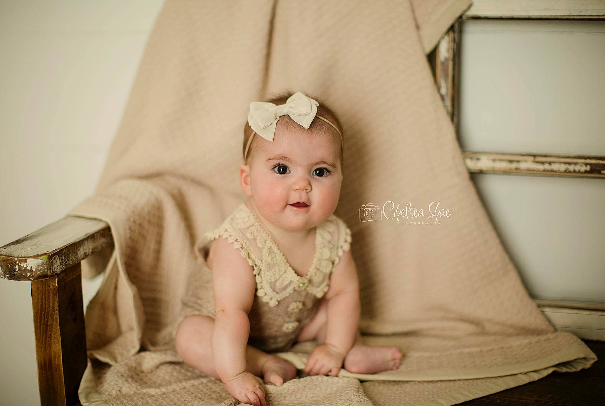 Anniston is registered to the contest to win money with this photo: baby, cheek, child, dress, eye, face, furniture, hair_accessory, head, headgear, headpiece, human, iris, person, photograph, photography, product, sitting, skin, smile