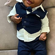 Jelany a rejoint le concours — aidez-le/la à gagner de superbes lots ! baby, child, smiling, face, vest, bow_tie, pants, shirt, couch, indoor, person, happy, clothing, footwear, sitting, portrait, cute, infant, black_hair, hands
