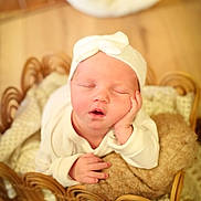 Ambre a rejoint le concours — aidez-le/la à gagner de superbes lots ! baby, newborn, infant, sleeping, basket, knit_hat, bow, blanket, cozy, portrait, face, hand, soft_focus, warm_tones, wood_floor, props, cute, peaceful, studio_photography, newborn_session